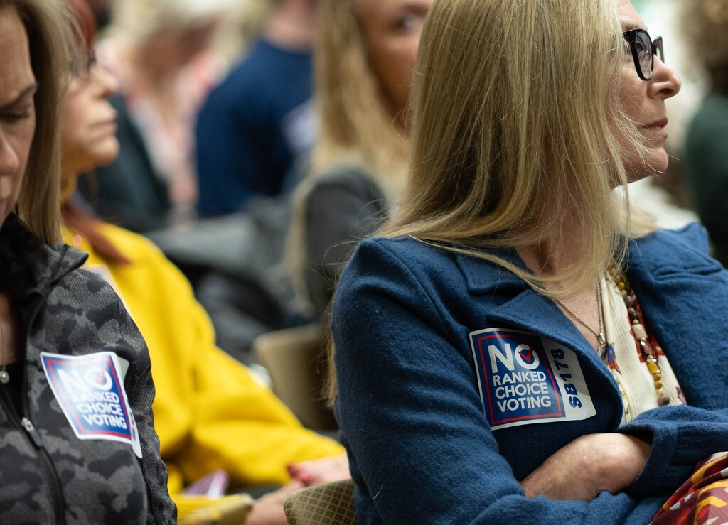 (Francisco Kjolseth | The Salt Lake Tribune) Opponents of a bill to expand the use of rank choice voting, distribute stickers to people attending a hearing on the the measure at the Utah Capitol on Wednesday, Feb. 9, 2022, before the bill was yanked from the agenda shortly before the meeting started. 