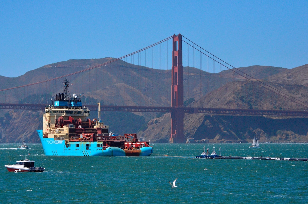 FILE- In this Sept. 8, 2018 file photo, a ship tows The Ocean Cleanup's first buoyant trash-collecting device toward the Golden Gate Bridge in San Francisco en route to the Pacific Ocean. A trash collection device deployed to corral plastic litter floating between California and Hawaii will be hauled back to dry land for repairs. Boyan Slat, who launched the Pacific Ocean cleanup project, tells NBC the 2,000-foot (600-meter) long floating boom will be towed to Hawaii. If it can't be repaired there it will be loaded on a barge and returned to its home port of Alameda, Calif. The boom broke apart under constant wind and waves. Slat says he's disappointed, but not discouraged. (AP Photo/Lorin Eleni Gill, File)