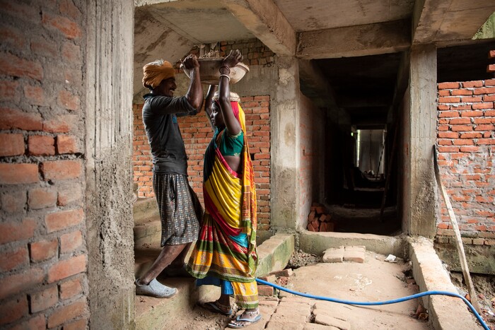 (Saumya Khandelwal | The New York Times) Rabita and her husband Ashok Kumar, carry sand up a stairwell, a task they repeat all day at the construction site where they both work and live in Lucknow, India, July 28, 2020. Rabita and her husband are Dalits, at the bottom of the Hindu caste ladder, working to pay off their debts.