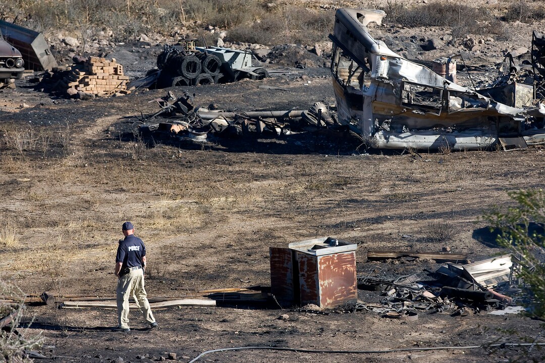 (Al Hartmann  |  Tribune file photo)  In this 2010 file photo, a police officer takes in the damage of a home in Herriman, Utah. It was one of the three homes burned in the Machine Gun Fire that year. The fire forced evacuations in Herriman and started a discussion about whether the Utah National Guard should remain at Camp Williams. Troops on the camp's firing range started the blaze.