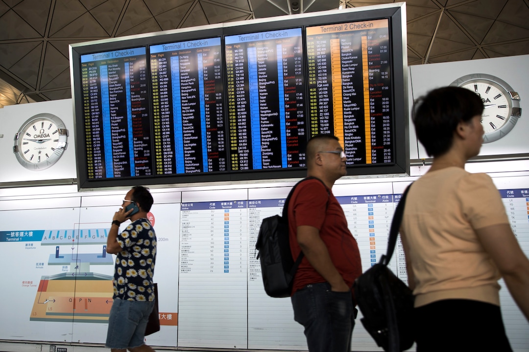 (Vincent Thian | AP Photo) Travelers walk past a flights information board at the Hong Kong International airport in Hong Kong, Tuesday, Aug. 13, 2019. Protesters clogged the departure area at Hong Kong's reopened airport Tuesday, a day after they forced one of the world's busiest transport hubs to shut down entirely amid their calls for an independent inquiry into alleged police abuse.