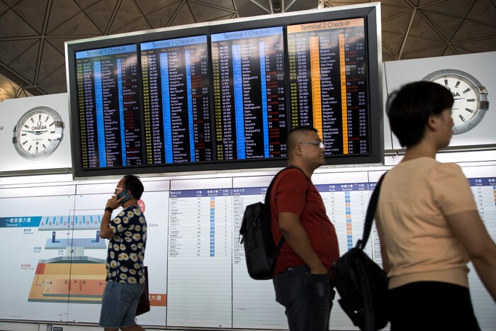 (Vincent Thian | AP Photo) Travelers walk past a flights information board at the Hong Kong International airport in Hong Kong, Tuesday, Aug. 13, 2019. Protesters clogged the departure area at Hong Kong's reopened airport Tuesday, a day after they forced one of the world's busiest transport hubs to shut down entirely amid their calls for an independent inquiry into alleged police abuse.