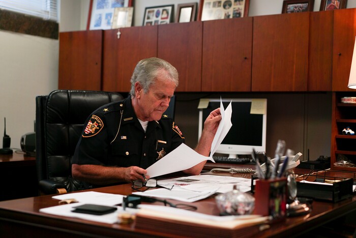 In this Aug. 9, 2017, photo, Lucas County Sheriff John Tharp looks through papers in his office in Toledo, Ohio. Police and rescue crews say drivers overdosing on heroin and other drugs are driving up the number of car crashes. Tharp says drivers in his county overdose on opioids so powerful it requires multiple doses of opiate antidote naloxone in order to revive them. (AP Photo/Dake Kang)