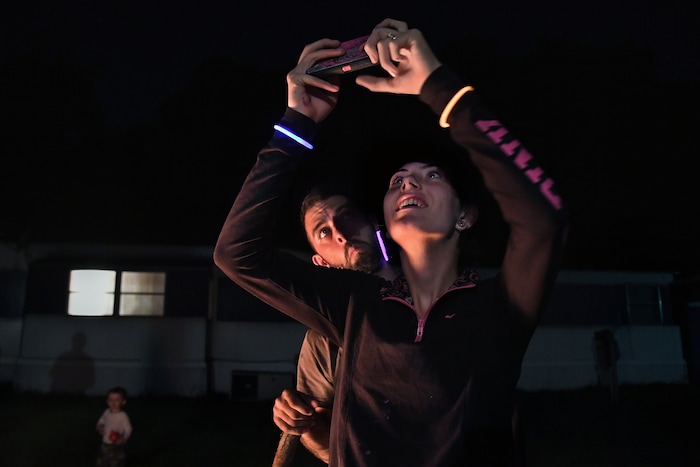 (Washington Post photo by Michael S. Williamson) Maria takes photos of a dramatic near-full moon over the mobile home they rent as her husband, Phi,l looks on.