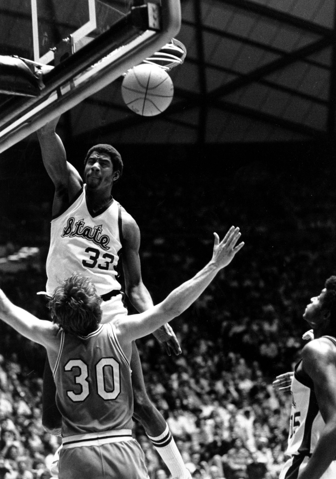 (AP Photo) Earvin "Magic" Johnson of Michigan State slams one home as he collides with Indiana State's Bob Heaton during their NCAA championship game in Salt Lake City on March 27, 1979. 