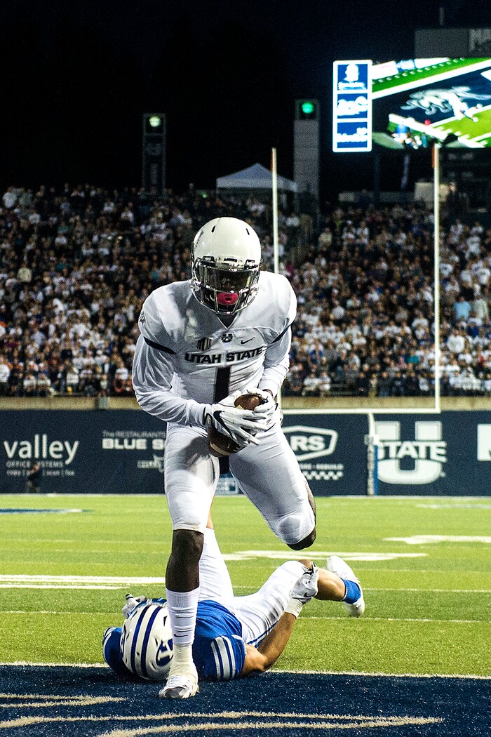 (Chris Detrick  |  The Salt Lake Tribune)  Utah State Aggies wide receiver Ron'quavion Tarver (1) scores a touchdown past Brigham Young Cougars defensive back Troy Warner (1) during the game at Merlin Olsen Field at Maverik Stadium Friday, September 29, 2017.
