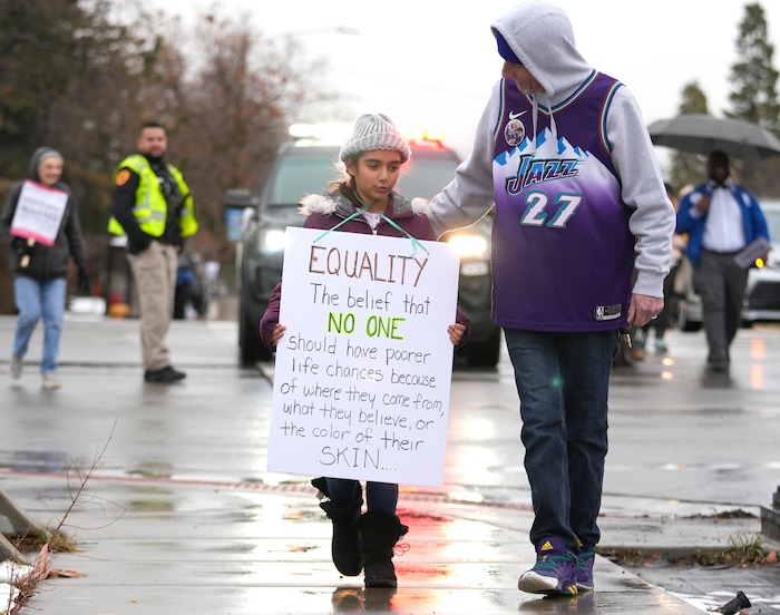 (Leah Hogsten | The Salt Lake Tribune) Ed Kirby, right, and his granddaughter Aneveah Lanzalaca participate in the march from East High School to Kingsbury Hall on Monday. To commemorate the legacy and work of Martin Luther King, Jr. and many other activists fighting for racial equality during the Civil Rights movement, the University of Utah's office of Equity, Diversity & Inclusion kicked off MLK Week 2023 with a rally at East High School, followed by a march to Kingsbury Hall, Jan. 16, 2023. 