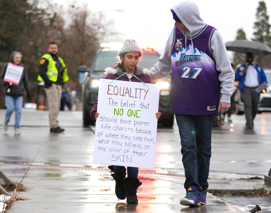 (Leah Hogsten | The Salt Lake Tribune) Ed Kirby, right, and his granddaughter Aneveah Lanzalaca participate in the march from East High School to Kingsbury Hall on Monday. To commemorate the legacy and work of Martin Luther King, Jr. and many other activists fighting for racial equality during the Civil Rights movement, the University of Utah's office of Equity, Diversity & Inclusion kicked off MLK Week 2023 with a rally at East High School, followed by a march to Kingsbury Hall, Jan. 16, 2023.