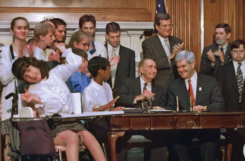 Ellen Richardson, of Fairfax, Va., left, joins congressional leaders on Capitol Hill Tuesday, June 3, 1997 for the signing of the Individuals with Disabilities Education Act Amendments. Seated from right are House Speaker Newt Gingrich, of Ga., and Sen. Strom Thurmond, R-S.C. Senate Majority Leader Trent Lott, of Miss., standing, applauds between them. (AP Photo/Ron Edmonds)