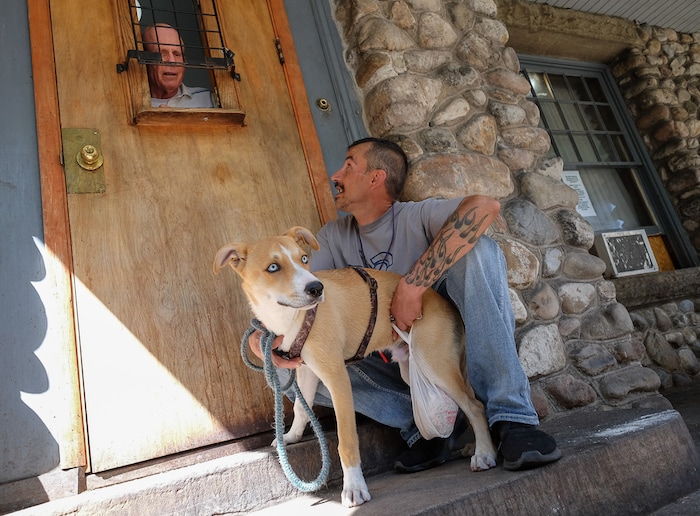 (Francisco Kjolseth  |  The Salt Lake Tribune)  Scott Helferty, a volunteer at the Good Samaritan House at 347 E. South Temple chats with Chad MaGee with his dog buster as he gets a dog treat and a sack lunch on Tuesday, Aug. 27, 2019. After 32 years of serving sack lunches 365 days a year for 11 hours a day to Utah's poor, the Good Samaritan will be closing down, absorbed into the Catholic church's operations at St. Vincent's.
