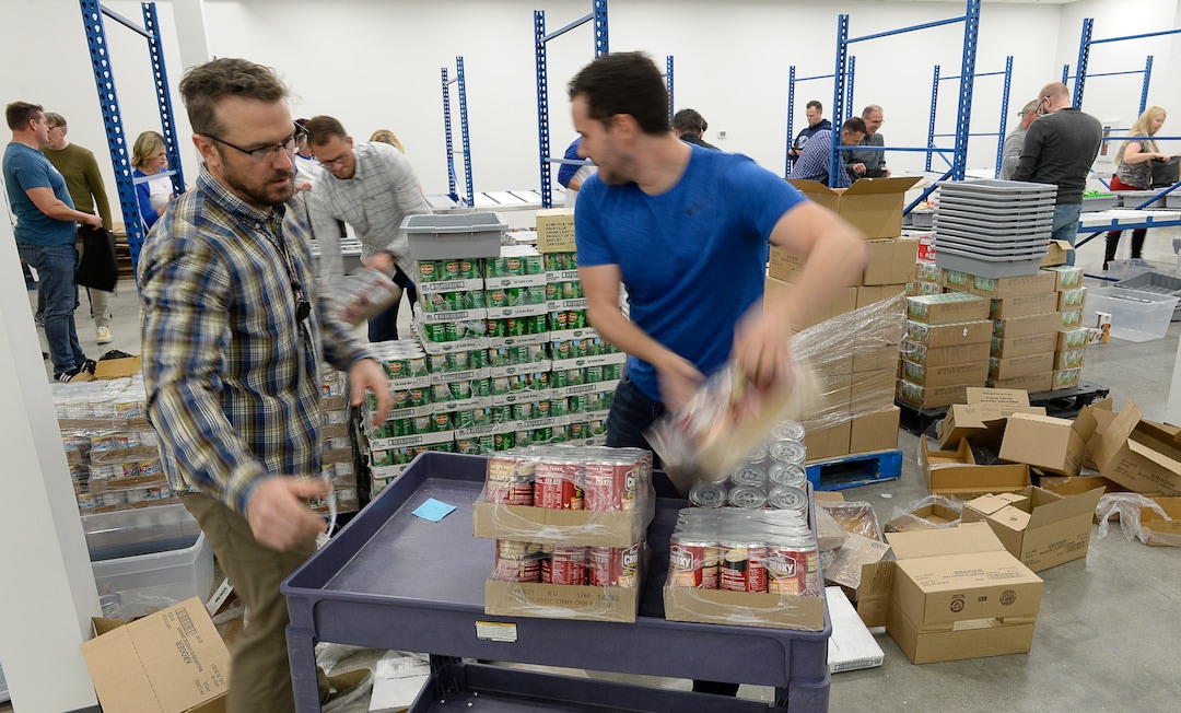 (Francisco Kjolseth  |  The Salt Lake Tribune)  John Bridge, left, and Brian Shostak join other USANA staff as they volunteer their time assembling food bags for at-risk youth at the newly-renovated packing and storage facility next to the headquarters of the Salt Lake City company on Wed. Dec. 11, 2019. The USANA Foundation has acquired two local charities, Kids Next Door and KidsEat!, that provides hundreds of food bags every week for the kids for the weekends and during long school breaks.