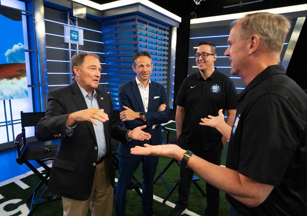 (Francisco Kjolseth | The Salt Lake Tribune) Former Gov. Gary Herbert, left, talks with BYU athletic director Tom Holmoe during BYU Football Media Day at the BYU Broadcasting Building in Provo on Thursday, June 17, 2021. Derek Miller, president and CEO of the Salt Lake Chamber and Downtown Alliance, center left, and Gary Veron, BYU associate athletic director for student-athlete experience, listen in following a televised broadcast.