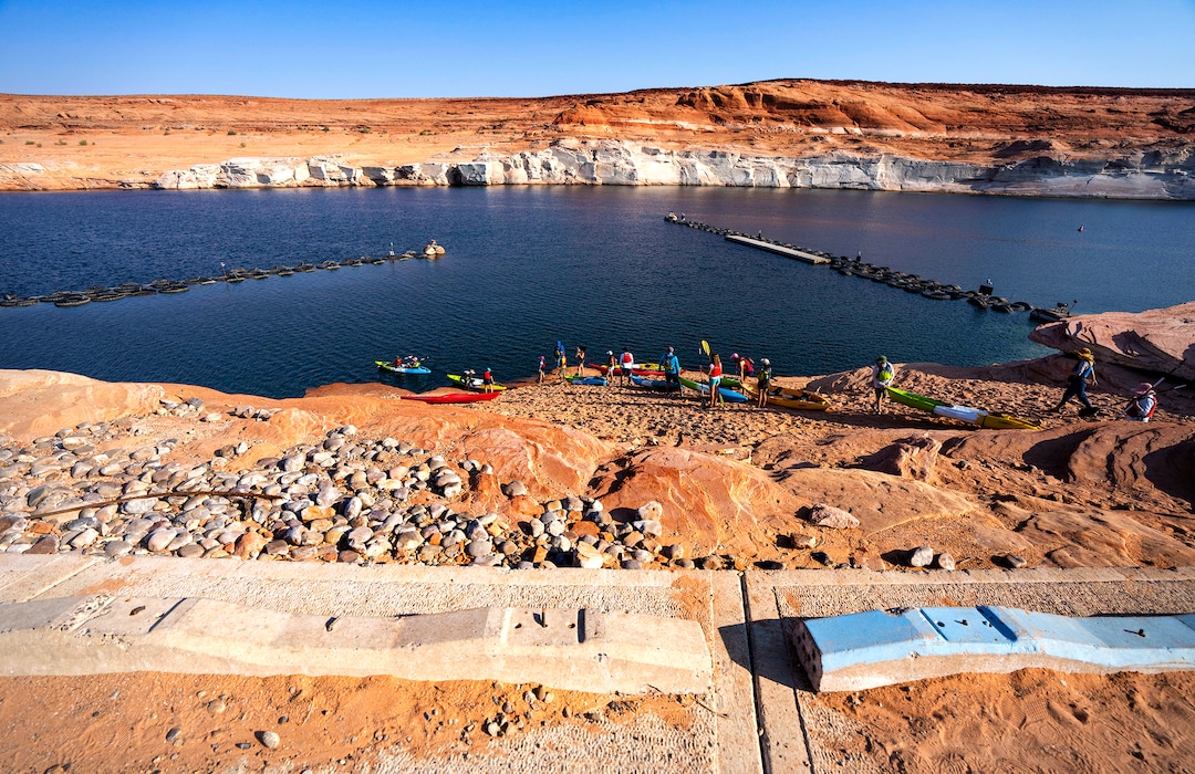 (Rick Egan | The Salt Lake Tribune) Due to the low water levels, Kayakers have to haul their kayaks another 30-50 yards to the water past the abandoned Antelope Public Launch Ramp, at Lake Powell, on Wednesday, Aug. 4, 2021. Water levels are dropping a few inches a day, which may bring an early end to kayaking on the lake in the next week or so, shortening a season that usually goes through the end of October.