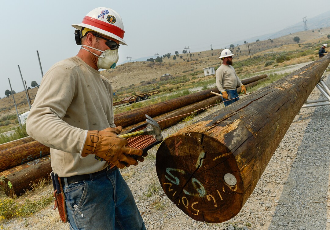 (Francisco Kjolseth  |  The Salt Lake Tribune)  Dakota Nielsen, an apprentice lineman for Rocky Mountain Power, wears a mask while working on replacement power poles burned down along U.S. Highway 6 in the Coal Hollow Fire on Saturday, Aug. 11, 2018. Occasionally, he can see the ash falling. "The less stuff in my lungs the better," Nielsen said. "It's been really bad."