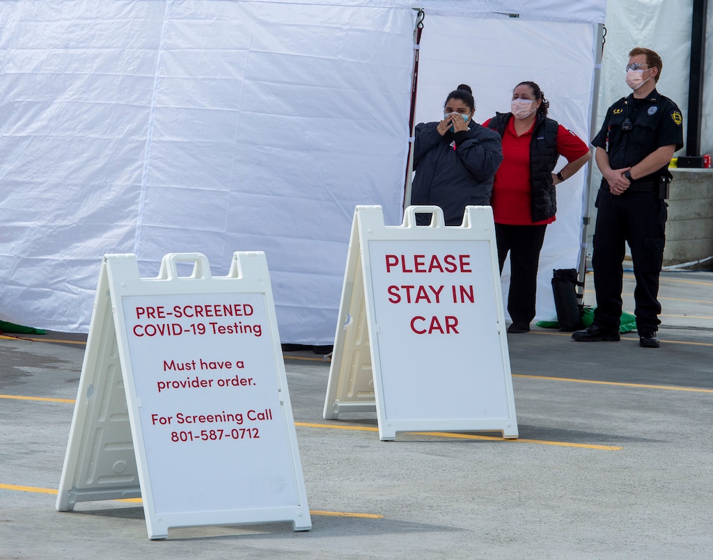 (Rick Egan  |  The Salt Lake Tribune) Health workers and security wait at a drive-up COVID—19 evaluation and testing at the University health Sugarhouse location, Friday, March 20, 2020.