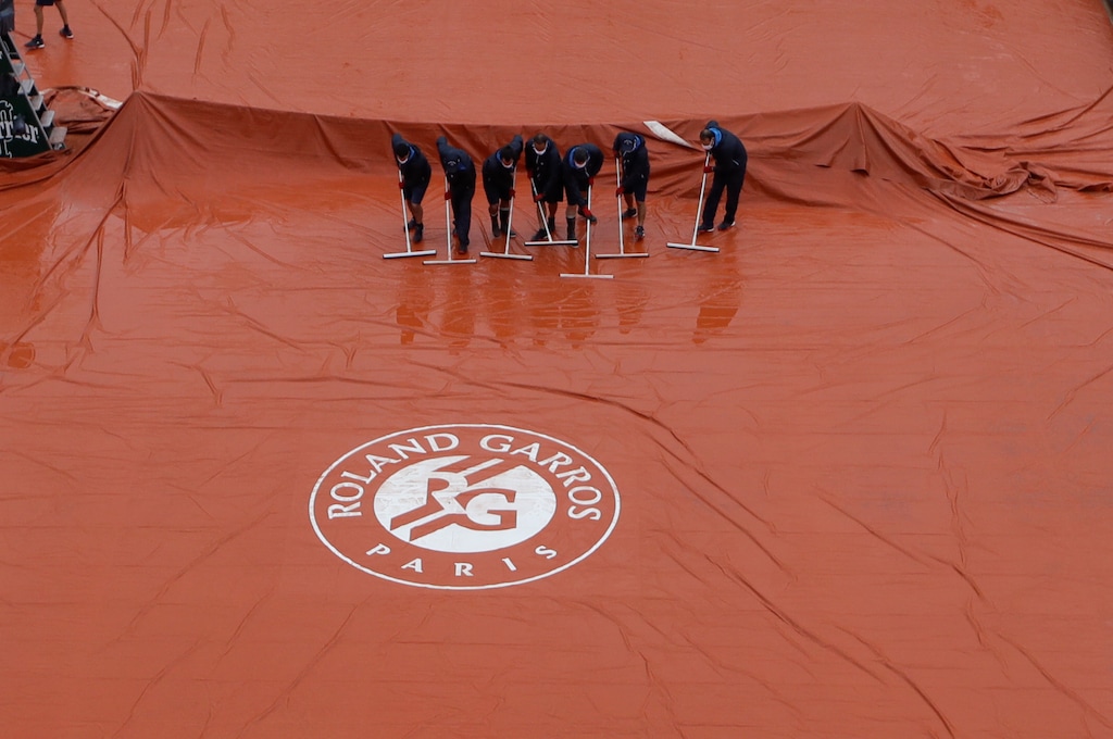 Stadium workers remove rain water from the cover of Suzanne Lenglen court as rain delayed fourth round matches of the French Open tennis tournament at the Roland Garros stadium in Paris, France, Monday, Oct. 5, 2020. (AP Photo/Alessandra Tarantino)