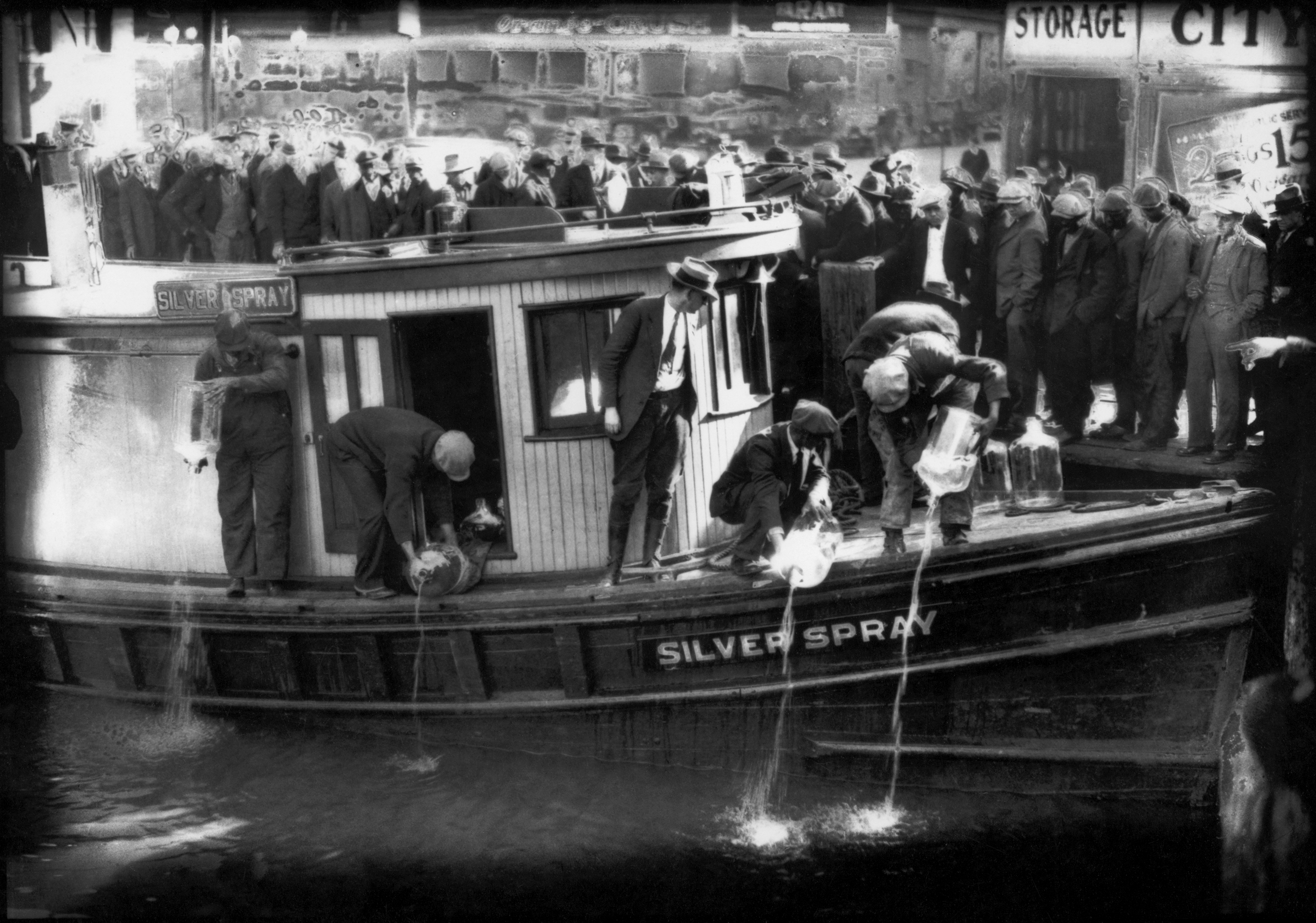 FILE - In this 1922 file photo spectators gather by the side of captured rum runner, Silver Spray, as they watch prohibition agents pour "white lightning" from the five-gallon bottles on the deck into the Elizabeth River, Norfolk, Va. The Prohibition Era, which lasted from Jan. 17, 1920, until December 1933, is now viewed as a failed experiment that glamorized illegal drinking. (Charles S. Borjes/The Virginian-Pilot via AP)
