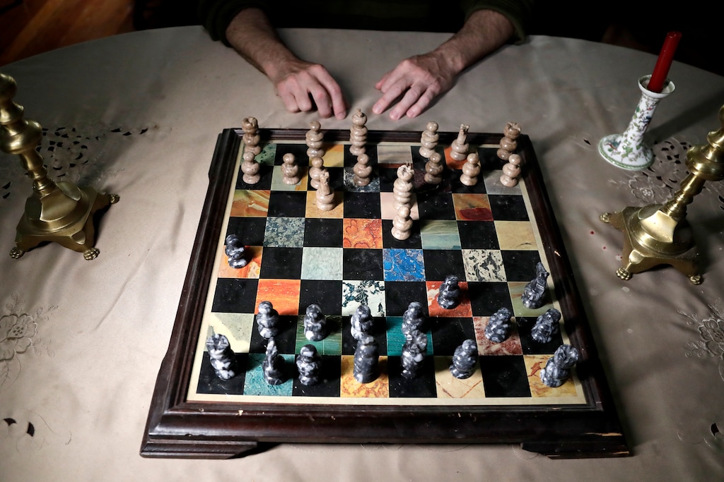 (Julio Cortez |AP) In 2019, a man poses for The Associated Press at an open-ended chess game he has with his roommate in his home in Plainfield, N.J.