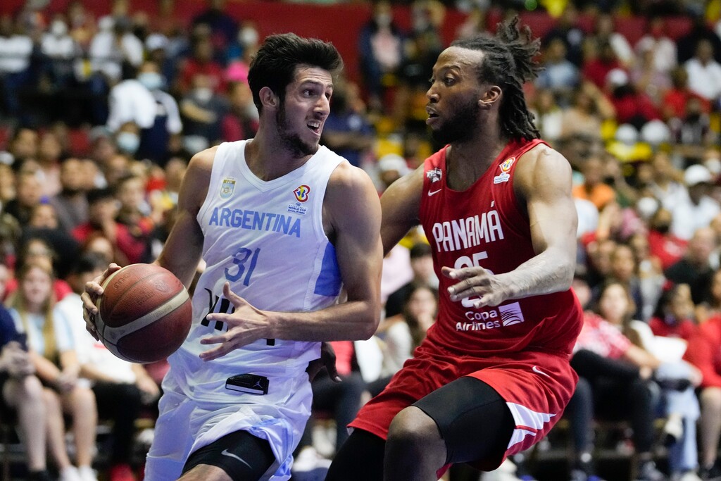 Argentina's Leandro Nicolas Bolmaro, left, looks to drive against Panama's Akil Mitchell during their FIBA Americas qualifiers for the 2023 Basketball World Cup at Roberto Duran arena in Panama City, Sunday, July 3, 2022. (AP Photo/Arnulfo Franco)