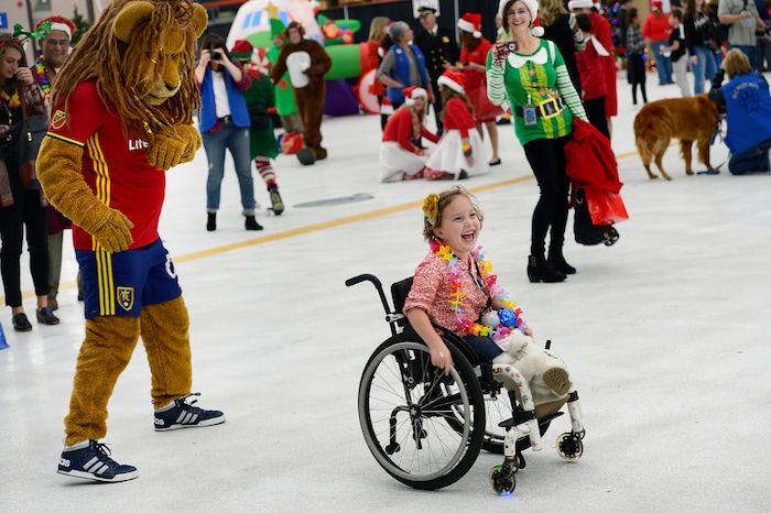 (Scott Sommerdorf   |  The Salt Lake Tribune)   Penelope Pedersen has fun with the RSL mascot "Leonardo the Lion" as patients from Primary ChildrenÕs and Shriners Hospitals were treated to a unique experience on Saturday at a Delta hangar of the Slat Lake International airport. They boarded a Boeing 737 which taxied to their final destinationÑSantaÕs Winter Wonderland, Saturday, December 2, 2017.  