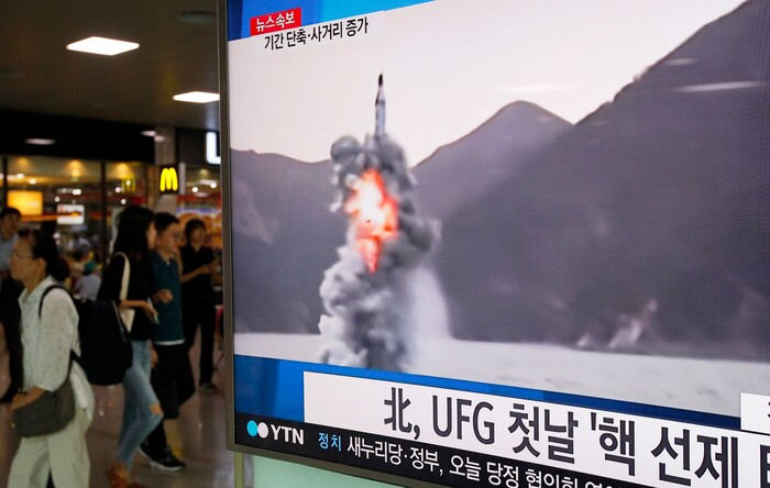 FILE- In this Aug. 24, 2016 file photo, people pass by a TV news program showing a file footage of North Korea's ballistic missile that the North claimed to have launched from underwater, at Seoul Railway station in Seoul, South Korea. America’s annual joint military exercises with South Korea always frustrate North Korea. Some experts say North Korea is mainly focused on the bigger picture of testing its bargaining power against the United States with its new long-range missiles and likely has no interest in letting things get too tense during the drills. The letters read: "North Korea fired a missile during UFG, Ulchi Freedom Guardian." (AP Photo/Ahn Young-joon, File)