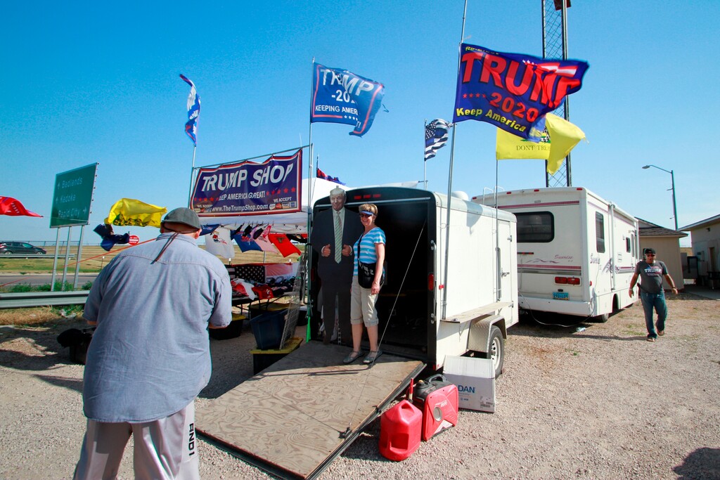 (Stephen Groves | AP)  Motorcycle riders on their way to the Sturgis Motorcycle Rally stop at a stand selling Trump displays in Wall, S.D., on Saturday, Aug. 8, 2020.