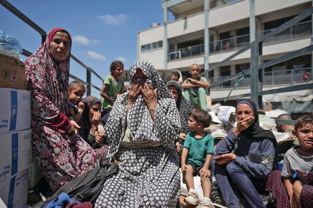 A Palestinian woman weeps on a truck during evacuation of a school that had been her shelter, in eastern Deir al-Balah, Gaza Strip, Friday, Aug. 16, 2024, after the Israeli military dropped leaflets asking civilians to evacuate from the area, saying forces plan to respond to rocket fire that targeted Israel. (AP Photo/Abdel Kareem Hana)