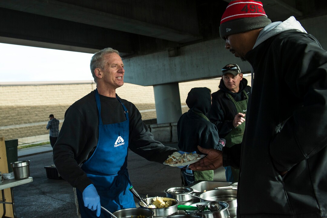 (Chris Detrick  |  The Salt Lake Tribune)  Volunteer Brent Levetan serves a Thanksgiving Day meal to Jason Hall during the Eagle Ranch Chuckwagon under the viaduct at 500 South and 600 West in Salt Lake City Thursday, November 23, 2017.  
