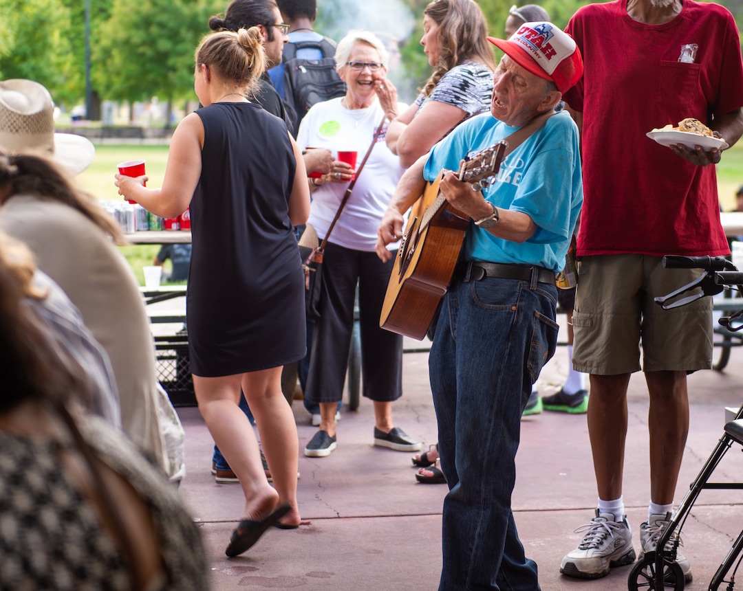 (Rachel Molenda  |  The Salt Lake Tribune) Dennis Keyting, center, plays the guitar at a candidate meet-and-greet held by Crossroads Urban Center at Liberty Park in Salt Lake City on Wednesday, July 11, 2018.