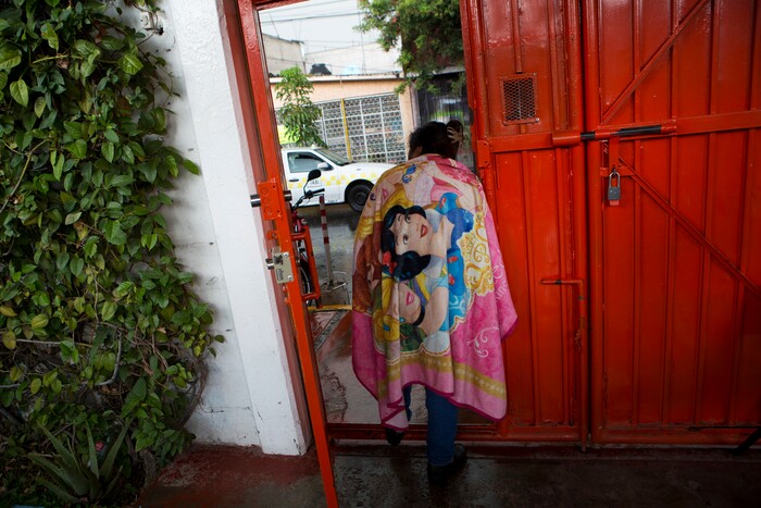 In this Aug. 25, 2017 photo, a cleaning lady looks out the door of a nursing school, monitored by a security guard, in Nezahualcoyotl, Mexico state. The mounting crisis of femicides _ murders of women where the motive is directly related to gender _ prompted the federal government to issue a gender violence alert in the State of Mexico in 2015. (AP Photo/Rebecca Blackwell)