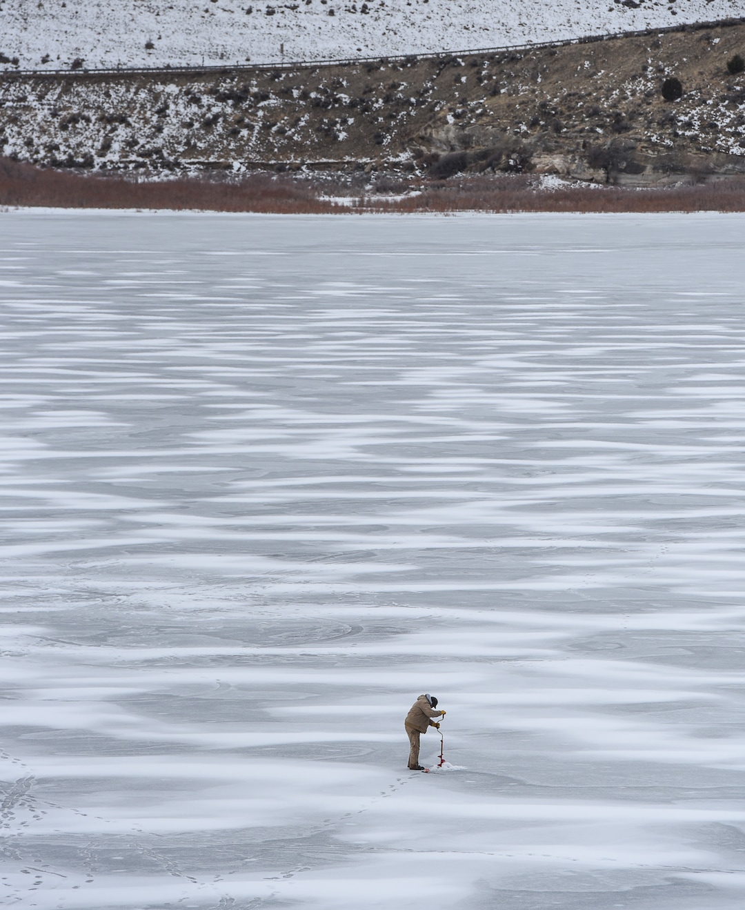 (Francisco Kjolseth  |  The Salt Lake Tribune)  An ice fisherman uses a hand powered auger to drill through the ice at Echo Reservoir in Summit County next to Coalville which could soon become a state park.