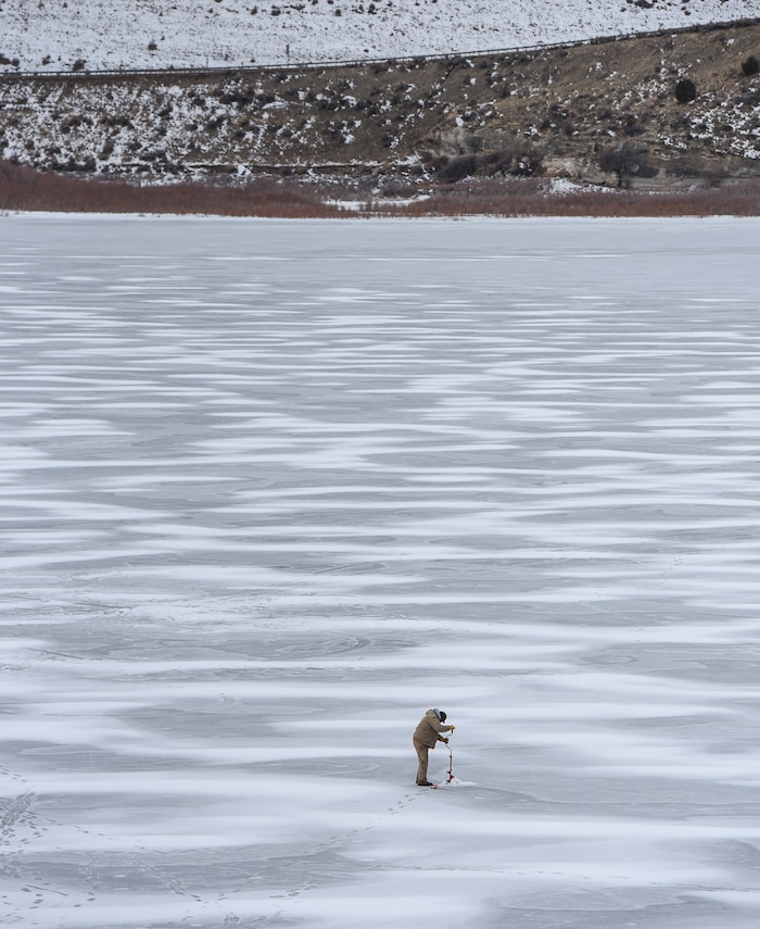 (Francisco Kjolseth | The Salt Lake Tribune) An ice fisherman uses a hand powered auger to drill through the ice at Echo Reservoir in Summit County next to Coalville which could soon become a state park.