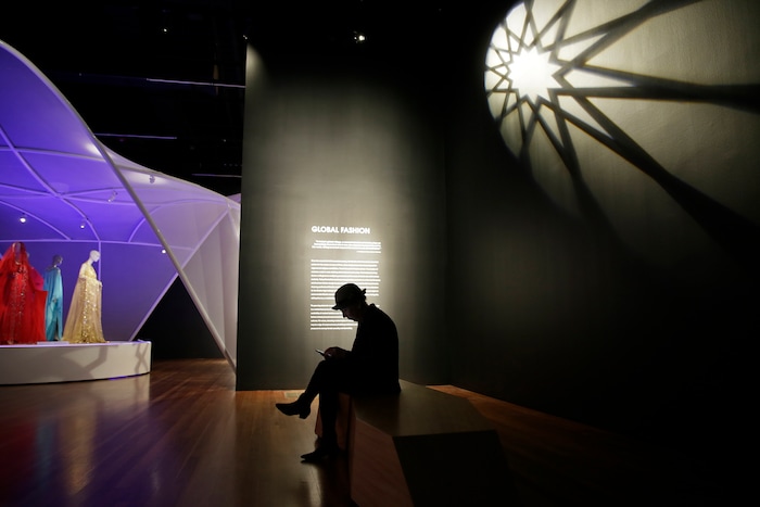 (Eric Risberg  |  AP Photo)  In this photo taken Thursday, Sept. 20, 2018, a man sits in a section on global fashions in the exhibit Contemporary Muslim Fashions at the M. H. de Young Memorial Museum in San Francisco. The first major museum exhibition of contemporary Muslim women's fashion reflects designs from around the world that are vibrant and elegant, playful and diverse. The show's creators hope the exhibit will show Muslim women as real people who can choose what they wear rather than as subjects ordered to cover their entire bodies or restricted in what they can wear. The exhibit opens on Saturday.