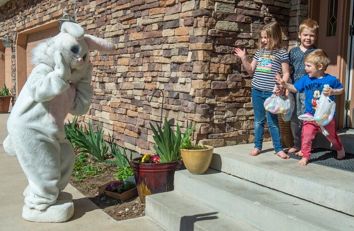 (Rick Egan  |  The Salt Lake Tribune)     Harper, Porter, and Everette Johnson wave at the Easter Bunny, from their front porch in Draper. Draper City Parks and Recreation workers along with the police and the fire department, delivered more than 30,000 Easter eggs to children at their doorsteps, Friday, April 10.