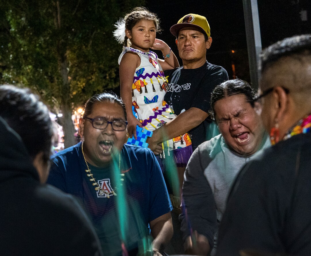 (Leah Hogsten | The Salt Lake Tribune Brady Tom and his daughter Major, 6, with the Kaibab band of the Paiute Indian Tribe of Utah watch the Sage Point drummers from Ft. Hall, ID close Friday evening of the 41st Annual Paiute Indian Tribe of Utah Restoration Gathering, Aug. 13, 2021 in Cedar City, Utah.