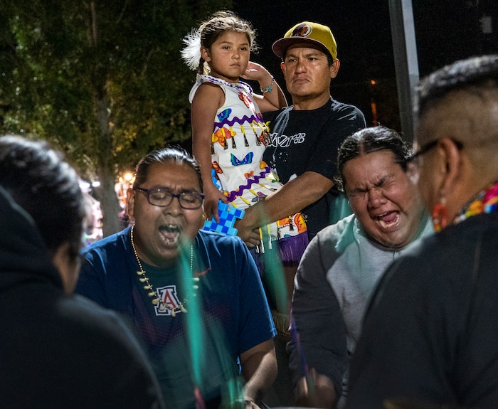 (Leah Hogsten | The Salt Lake Tribune Brady Tom and his daughter Major, 6, with the Kaibab band of the Paiute Indian Tribe of Utah watch the Sage Point drummers from Ft. Hall, ID close Friday evening of the 41st Annual Paiute Indian Tribe of Utah Restoration Gathering, Aug. 13, 2021 in Cedar City, Utah.