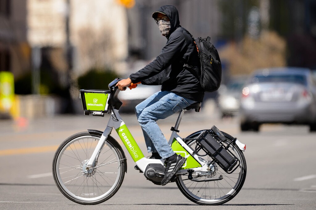 (Trent Nelson  |  The Salt Lake Tribune) A man riding a bike and wearing a mask in downtown Salt Lake City on Friday, April 10, 2020.