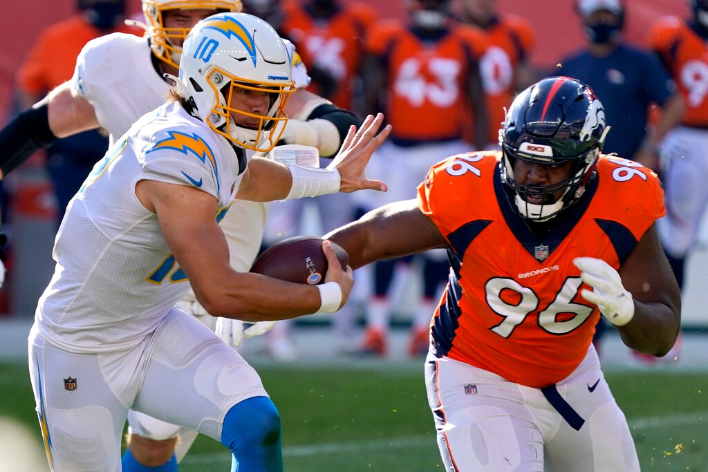 Los Angeles Chargers quarterback Justin Herbert (10) runs as Denver Broncos defensive end Shelby Harris (96) pursues during the first half of an NFL football game, Sunday, Nov. 1, 2020, in Denver. (AP Photo/David Zalubowski)