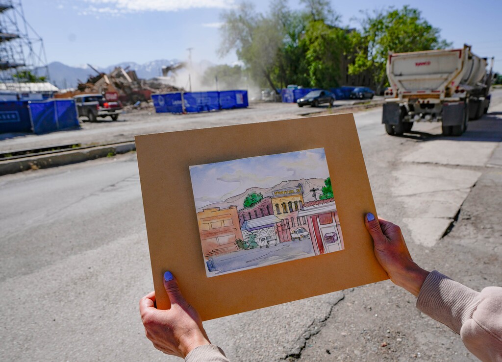 (Francisco Kjolseth | The Salt Lake Tribune) Anna Moore, a local landscape painter and “protector of all things historic, beautiful and wild,” is saddened as she holds up a painting she made years ago of the old Utah Pickle Company building as a developer tears down the building at 741 S 400 West on Thursday, May 22, 2025.