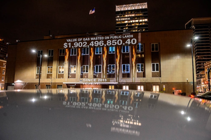 (Trent Nelson | The Salt Lake Tribune)
In a visual protest, Alliance for Better Utah projects the total dollar value of natural gas lost on public lands since 2013 due to venting, flaring, and leaking onto the side of Federal Reserve Building in Salt Lake City, Thursday April 5, 2018.