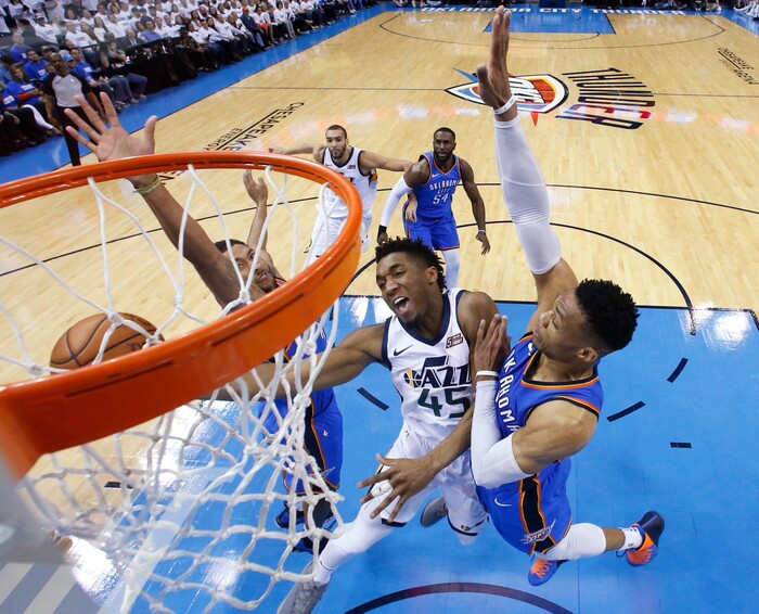 Utah Jazz guard Donovan Mitchell (45) shoots between Oklahoma City Thunder guard Josh Huestis, left, and guard Russell Westbrook, right, during the first half of Game 5 of an NBA basketball first-round playoff series in Oklahoma City, Wednesday, April 25, 2018. (AP Photo/Sue Ogrocki)