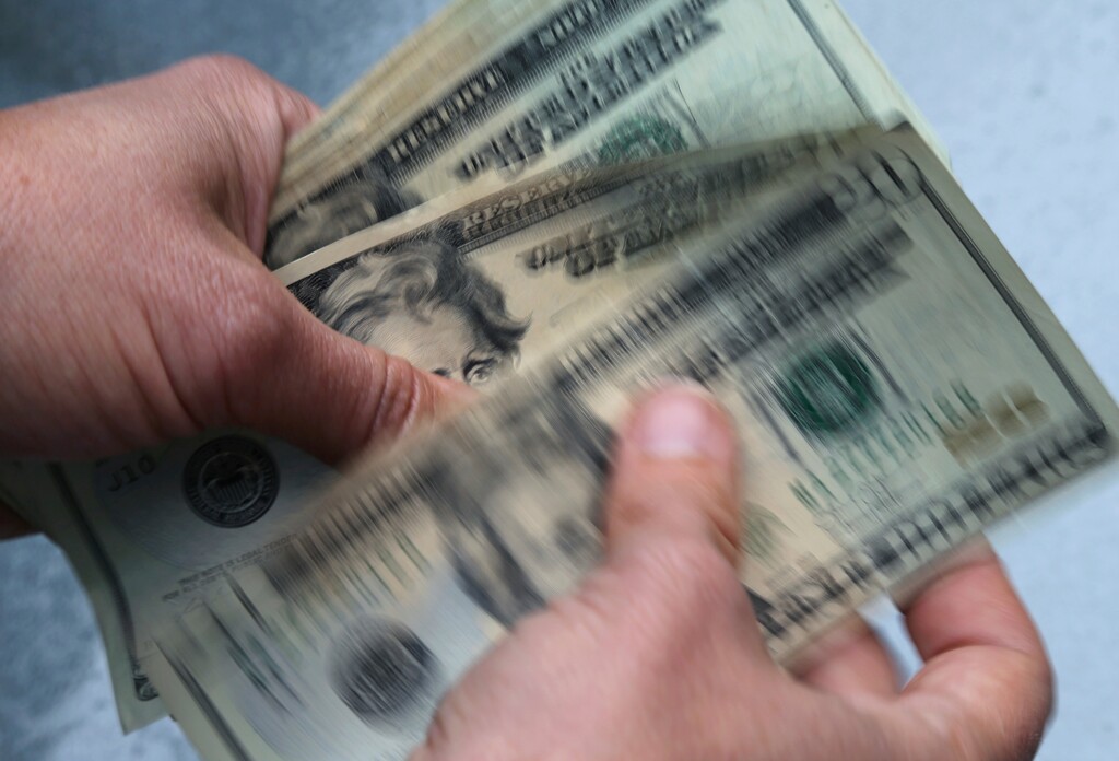FILE- In this June 15, 2018, file photo, twenty dollar bills are counted in North Andover, Mass. Default on your federal student loans and the government can take up to 15 percent of each paycheck to satisfy your debt. The Education Department can also withhold federal benefits like tax returns and Social Security payments. Garnishment is an effective tool to recoup unpaid loans, private collection agencies enlisted by the Education Department took in over $841.6 million via wage garnishment in the 2018 fiscal year, but it inflicts serious financial strain on borrowers who are already struggling. (AP Photo/Elise Amendola, File)