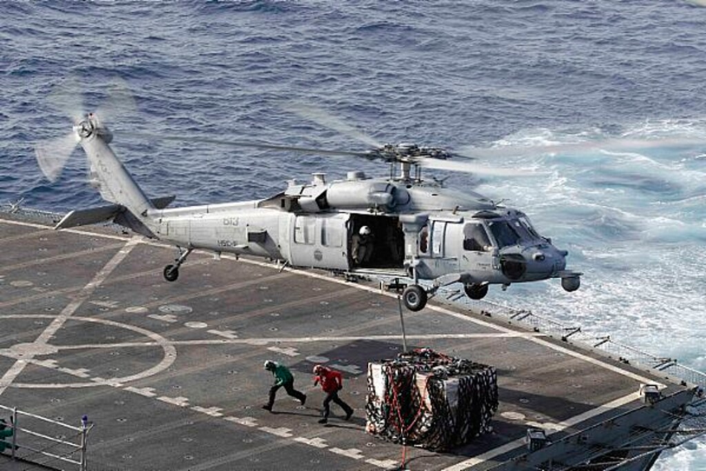 (Mass Communication Specialist 3rd Class Darion Chanelle Triplett/U.S. Navy via AP) In this Sunday, May 19, 2019 photo, an MH-60S Sea Hawk helicopter transports cargo from the fast combat support ship USNS Arctic to the Nimitz-class aircraft carrier USS Abraham Lincoln during a replenishment-at-sea operation in the Arabian Sea, as Mideast tensions remain high between Tehran and the United States.