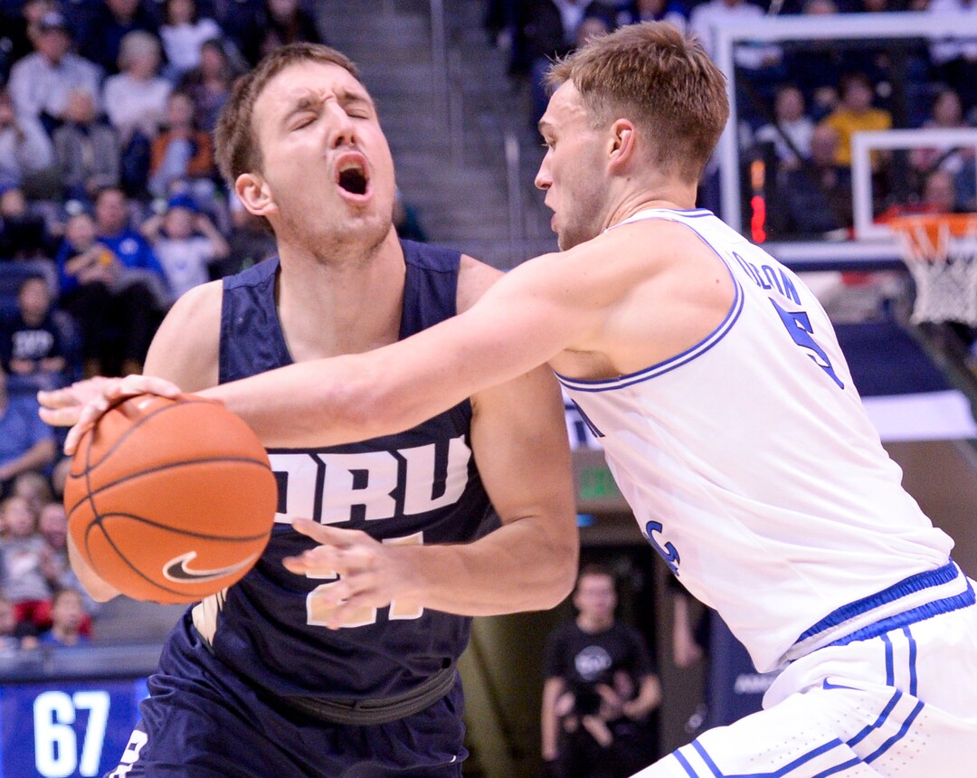 (Leah Hogsten  |  The Salt Lake Tribune) Oral Roberts Golden Eagles guard Ty Lazenby (21) is fouled by Brigham Young Cougars guard Jake Toolson (5). Brigham Young University defeated Oral Roberts, 79-73, Dec. 28, 2019 at the Marriott Center in Provo.