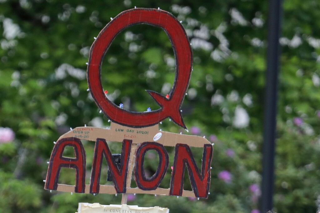 (Ted S. Warren | AP file photo)

In this May 14 photo, a person carries a sign supporting QAnon at a protest rally in Olympia, Wash. Facebook said Oct. 6 that it will remove Facebook pages, groups and Instagram accounts for “representing QAnon.”
