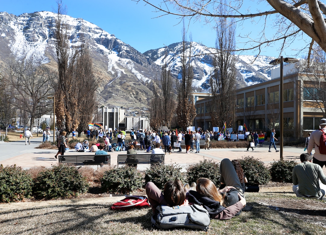 (George Frey  |  special to The Salt Lake Tribune) Two BYU students lay on the lawn and watch other BYU students in front of the Ernest L. Wilkinson Student Center on the campus of Brigham Young University protest BYUÕs rollback of a newly announced policy change on LGBTQ students on March 5, 2020 in Provo, Utah.