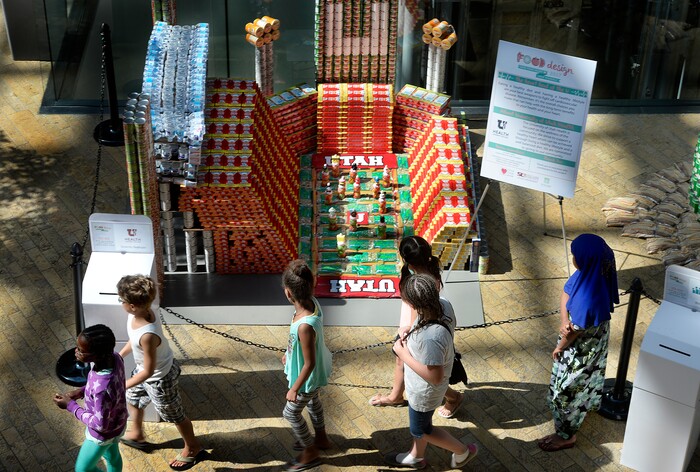 (Scott Sommerdorf | The Salt Lake Tribune) Visitors to the Salt Lake City Public Library walk past the University of Utah Health replica of Rice-Eccles Stadium as the library hosted a community display and food drive focused on healthy food items for the Utah Food Bank. Teams from six local health careÐrelated businesses built giant sculptures using healthy canned, bagged, and boxed foods. The replica of Rice-Eccles Stadium won the public choice award, Thursday, August 10, 2017.