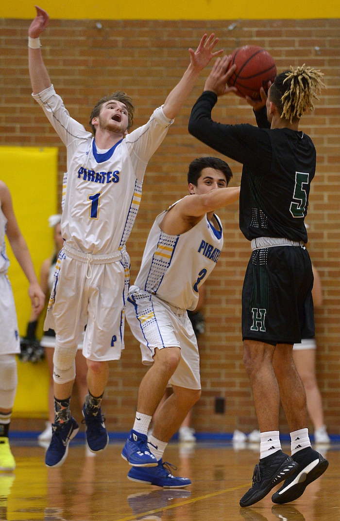 (Leah Hogsten | The Salt Lake Tribune) Cyprus' Alex Foster and Ben Ellsworth try to shot Hillcrest's Tyson Flores. Cyprus High School boys' basketball team defeated Hillcrest High School 77-61 during their game Tuesday, January 30, 2018 in Magna.