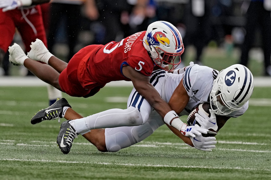 (Charlie Riedel | AP) BYU wide receiver Keanu Hill is tackled by Kansas safety O.J. Burroughs (5) during the first half of an NCAA college football game Saturday, Sept. 23, 2023, in Lawrence, Kan.