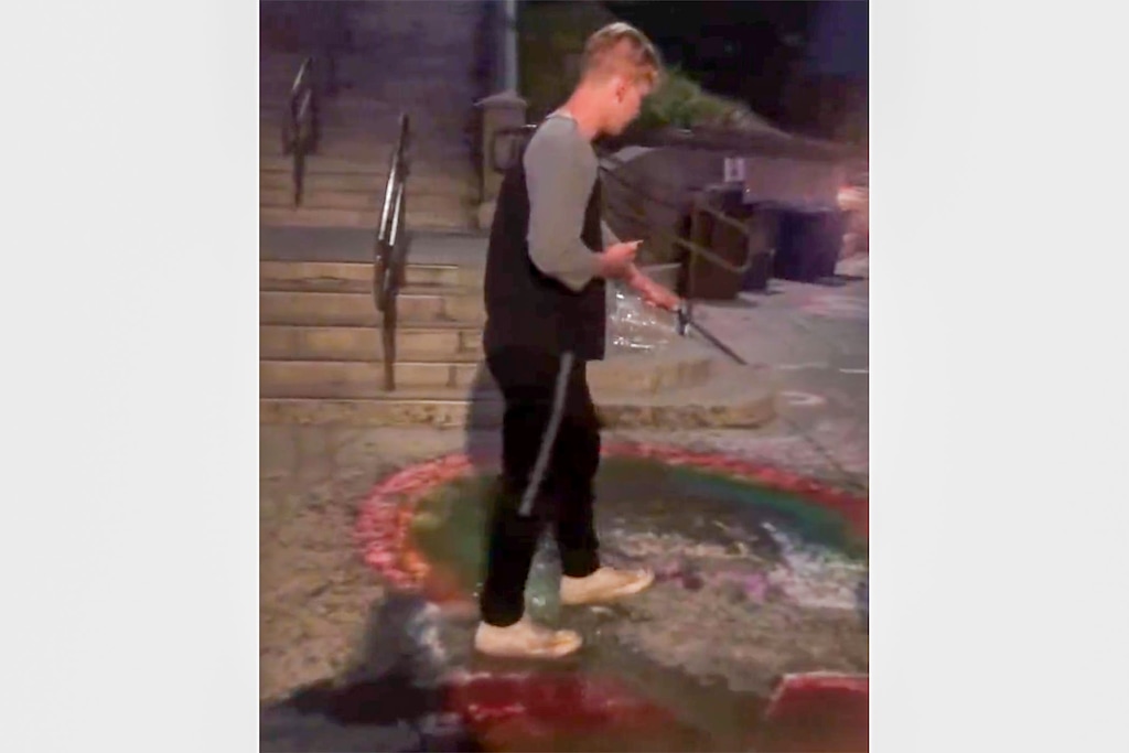 (Screenshot) Captured in a video, a man dumps water on sidewalk chalk art across from Brigham Young University that was meant to support LGBTQ students there on Thursday, August 26, 2021.